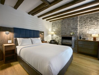 Schlafzimmer mit Bett und historischen Details wie freiliegenden Balken und Steinmauer